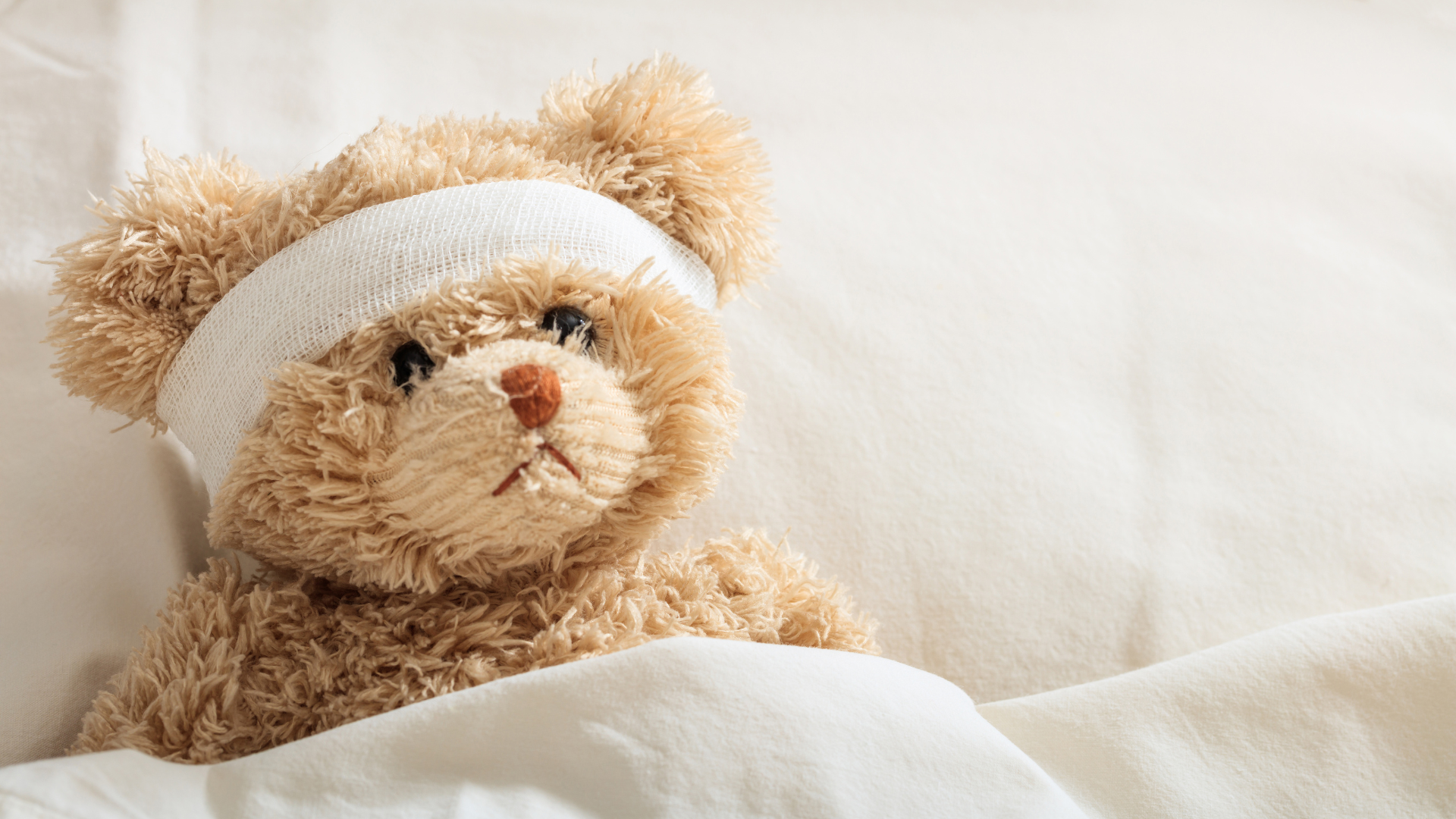 Teddy im Bett liegend mit verbundenem Kopf